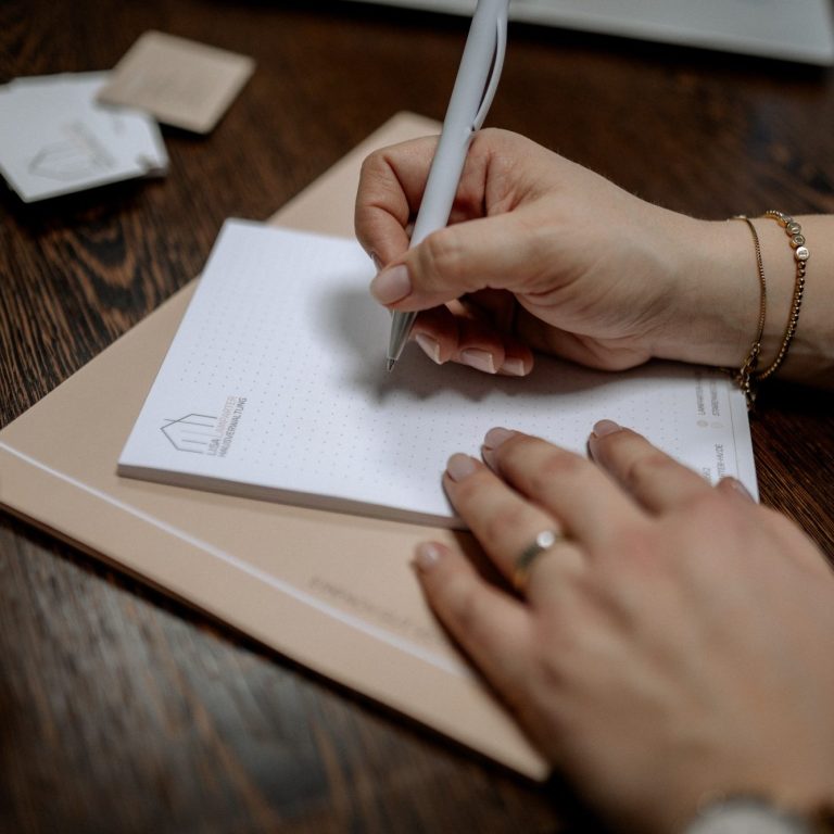 Arbeit Zu sehen sind zwei Hände mit Kugelschreiber in der Hand, welche auf den Block der Lisa Hausverwaltung schreiben.
